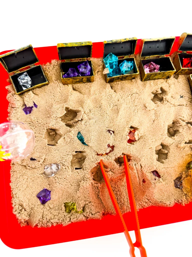 a Treasure Hunt Sensory Bin with kinetic sand, and gems in treasure chests