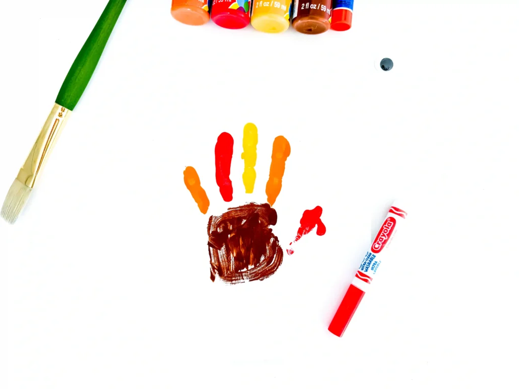 a handprint of brown, red, yellow, and orange paint to look like a turkey