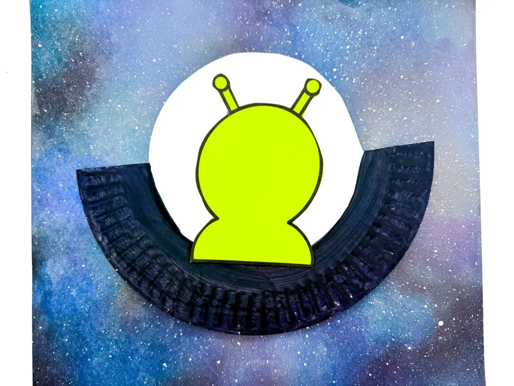 a paper plate cut to look like a UFO with an alien in it