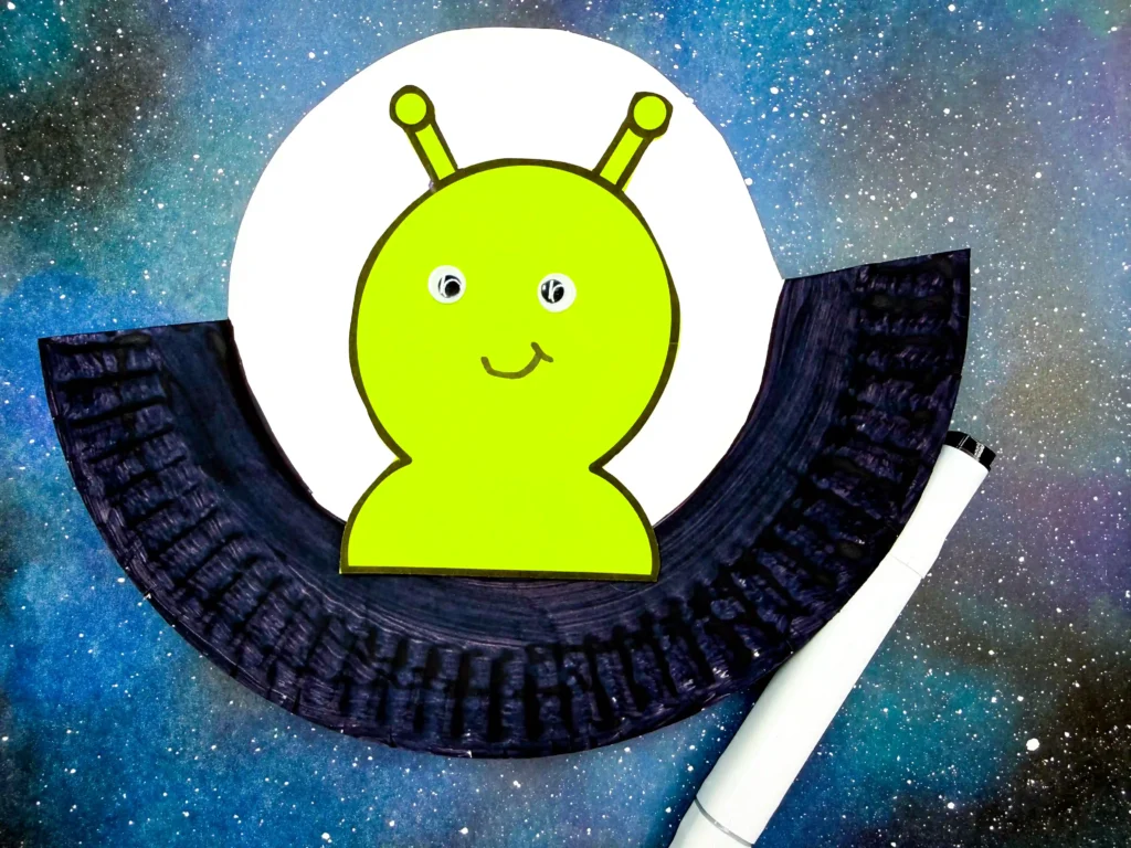 a paper plate cut to look like a UFO with an alien in it