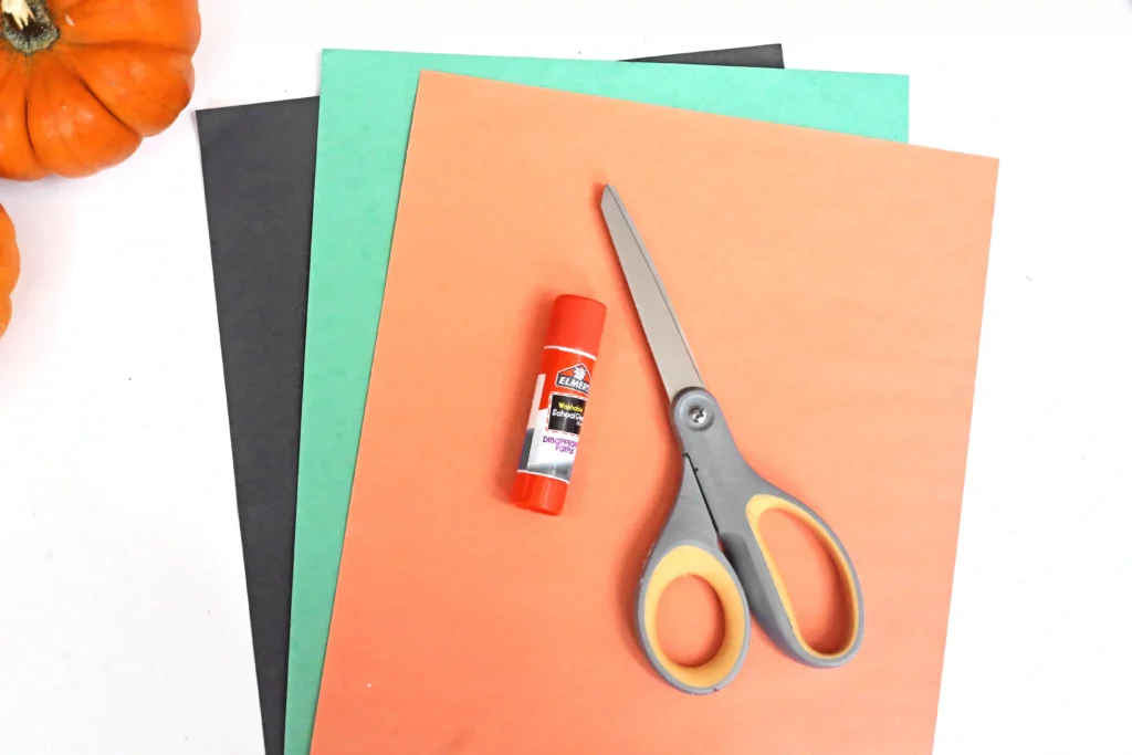 supplies for the jack-o-lantern craft: black, green, and orange construction paper, glue, and scissors