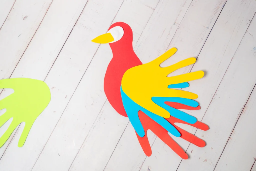 a parrot with handprint wings made out of construction paper