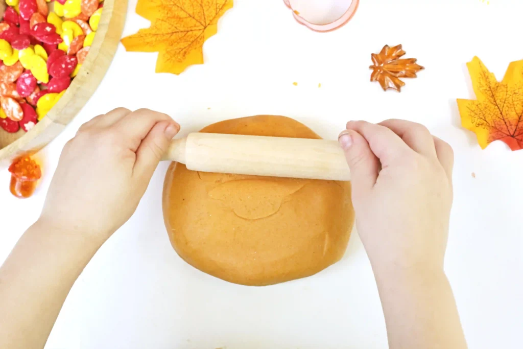 a kid using a rolling pin on playdough