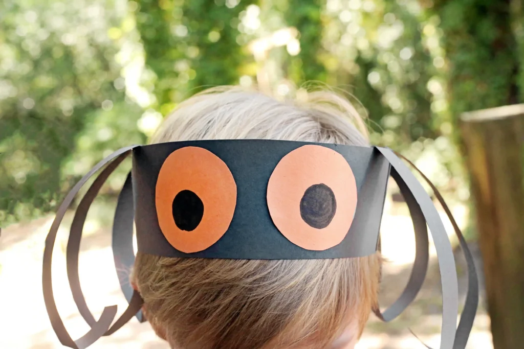 a kid wearing a construction paper headband that looks like a spider
