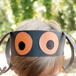 a kid wearing a construction paper headband that looks like a spider