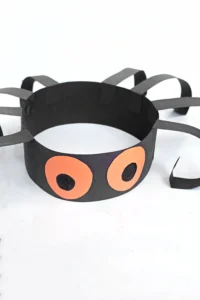 a construction paper headband that is decorated to look like a spider