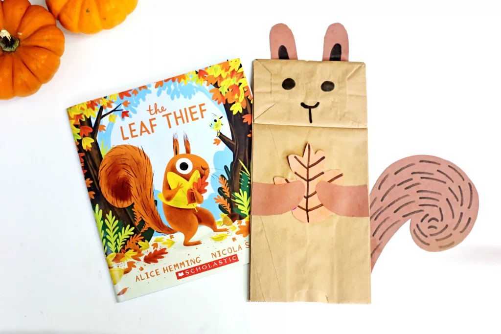 a paper bag decorated to look like a squirrel next to the book "The Leaf Thief"