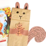 a paper bag decorated to look like a squirrel next to the book "The Leaf Thief"