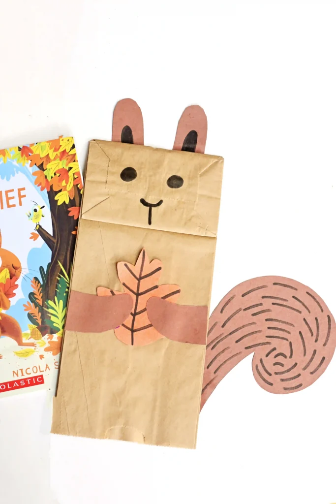 a paper bag decorated to look like a squirrel next to the book "The Leaf Thief"