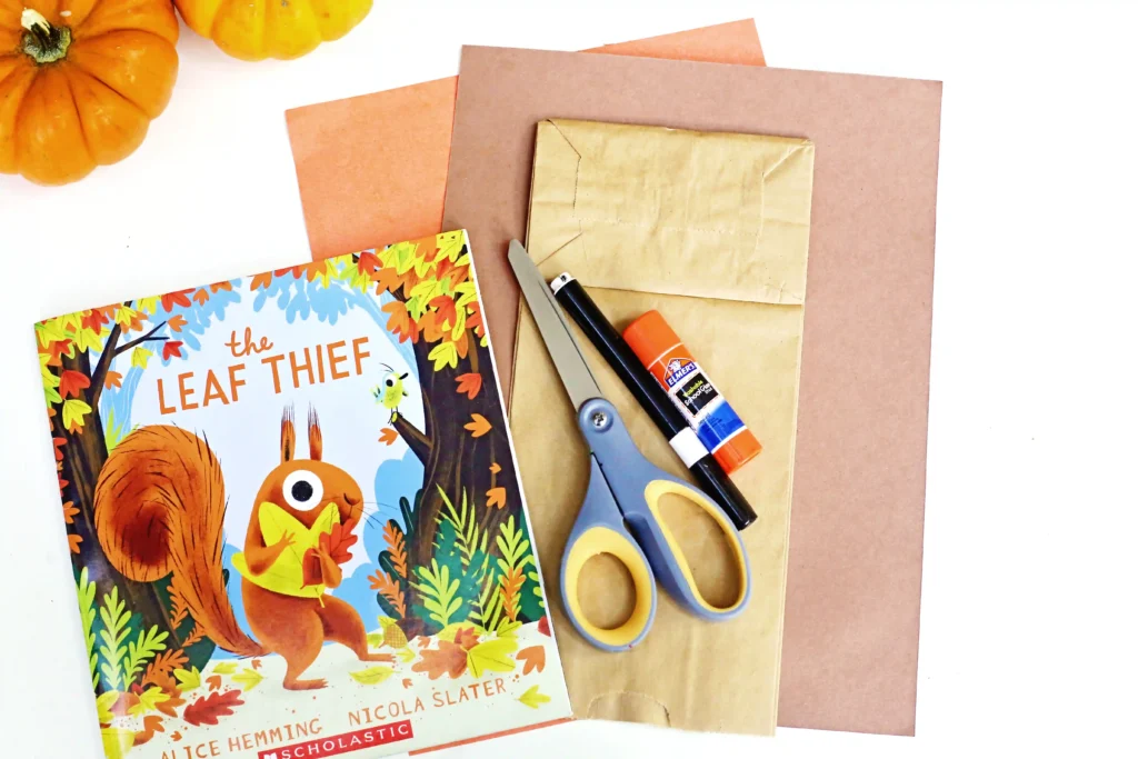 supplies for this squirrel paper bag craft: paper bag, brown and orange paper, scissors, glue, and a black marker