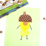 a handprint craft that is a yellow acorn with an orange nose