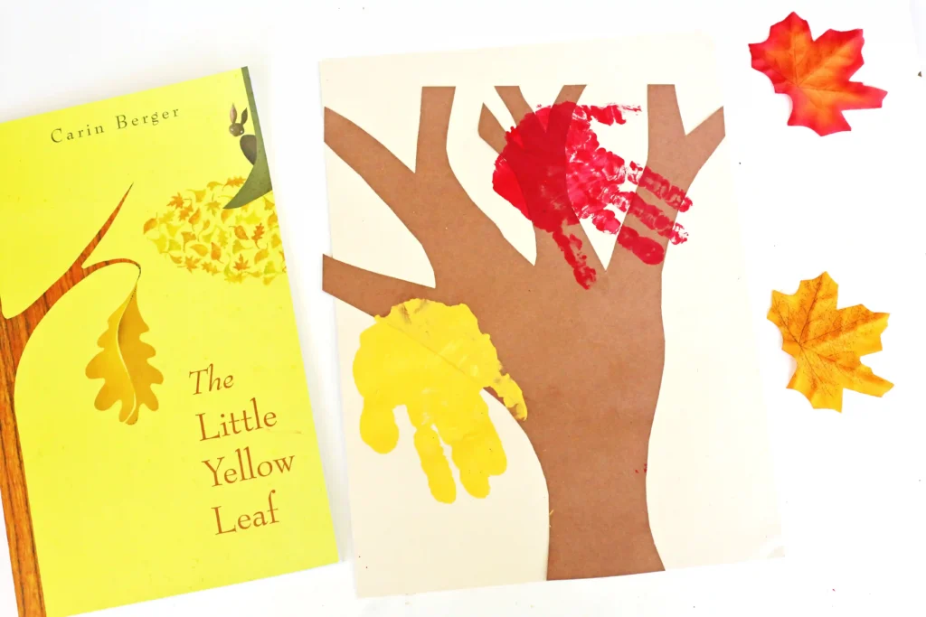 a tree cut out of construciton paper with red and yellow handprints to look like leaves