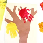 a tree cut out of construction paper with red and yellow handprints to look like leaves