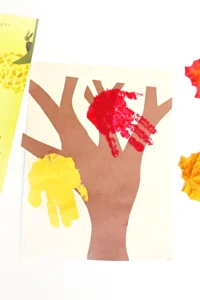 a tree cut out of construction paper with red and yellow handprints to look like leaves