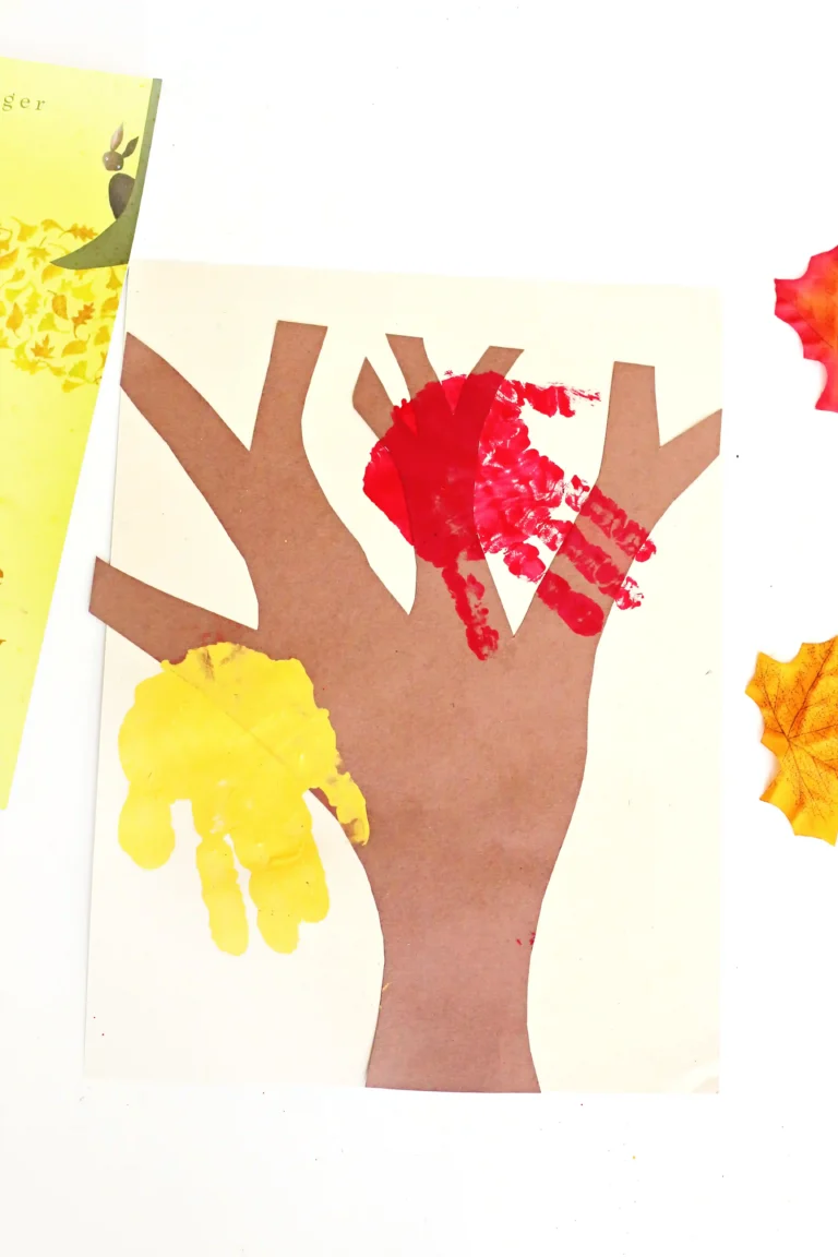 a tree cut out of construction paper with red and yellow handprints to look like leaves