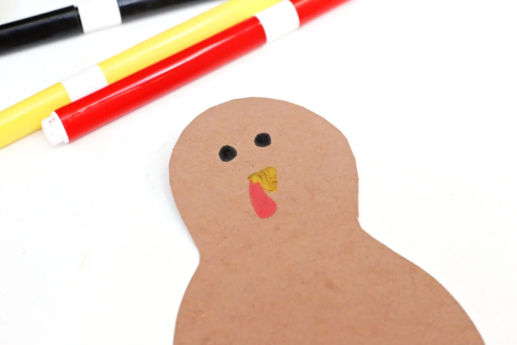 a turkey cut out of brown construction paper with eyes, a beak, and a snood drawn on