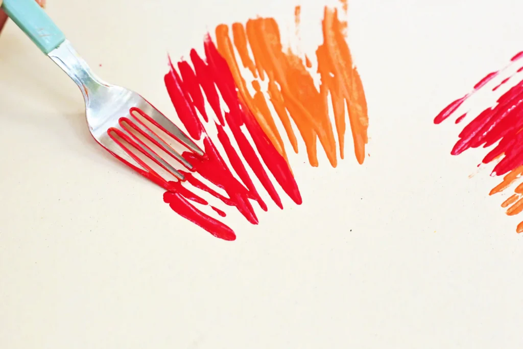 a fork putting paint on a cream colored paper