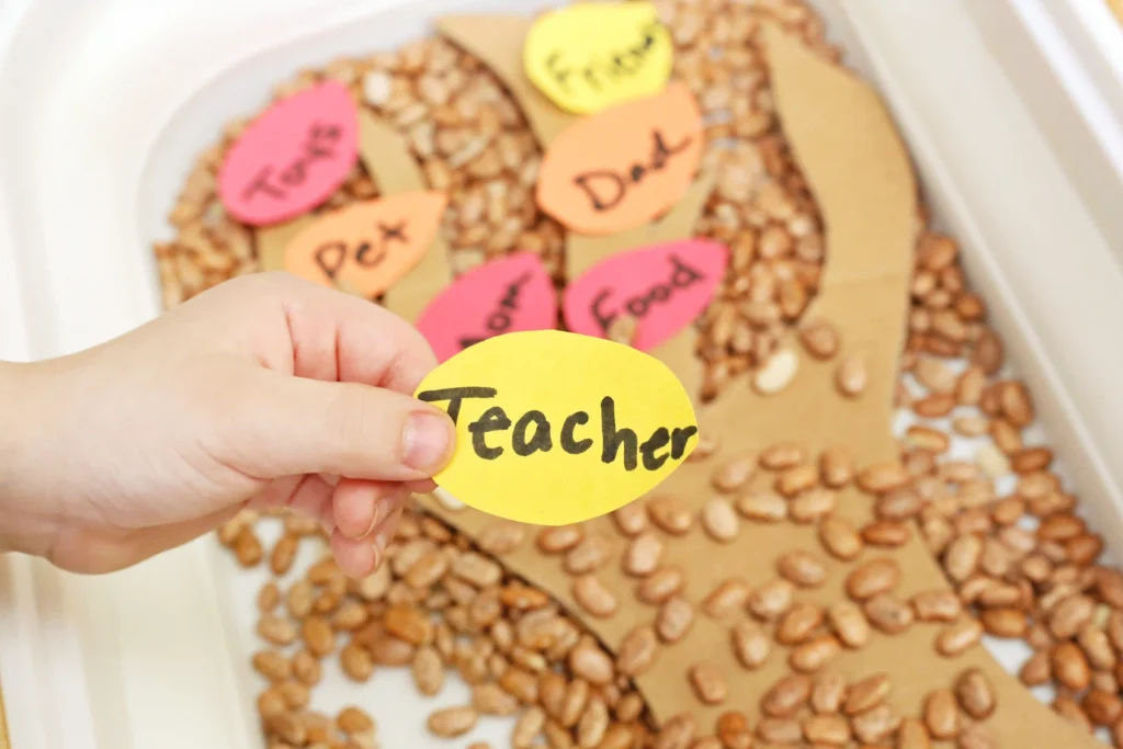 a kid holding a construction paper leaf that says teacher