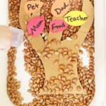 a thanksgiving sensory bin with dried beans, a cardboard tree, and construction paper feathers