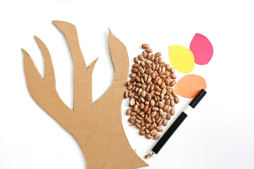 supplies for the thanksgiving sensory bin: cardboard, dried beans, construction paper, and a black marker