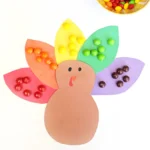 a construction paper turkey with skittles on the feathers to match their colors