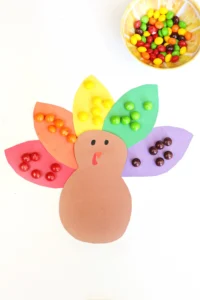 a construction paper turkey with skittles on the feathers to match their colors