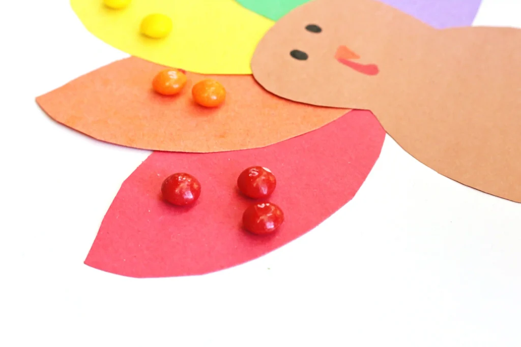 a construction paper turkey with skittles on the feathers to match their colors
