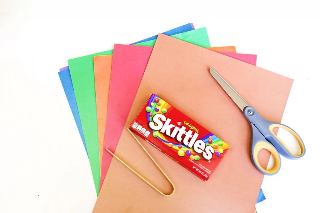supplies for the turkey color matching activity: colored construction paper, scissors, skittles, and tweezers