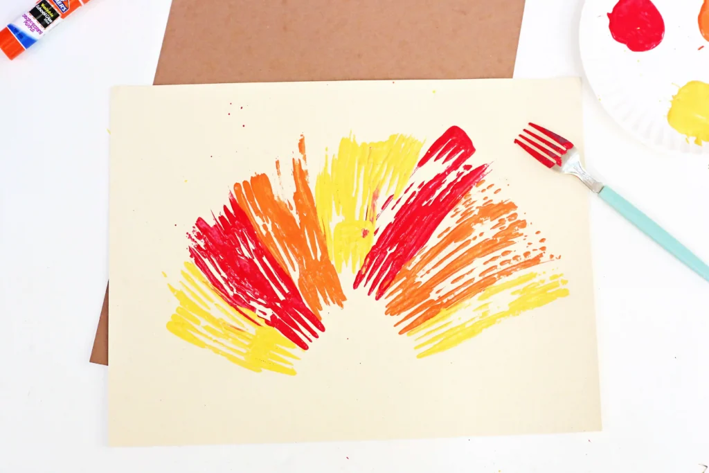 a cream piece of paper with orange, red, and yellow paint on it